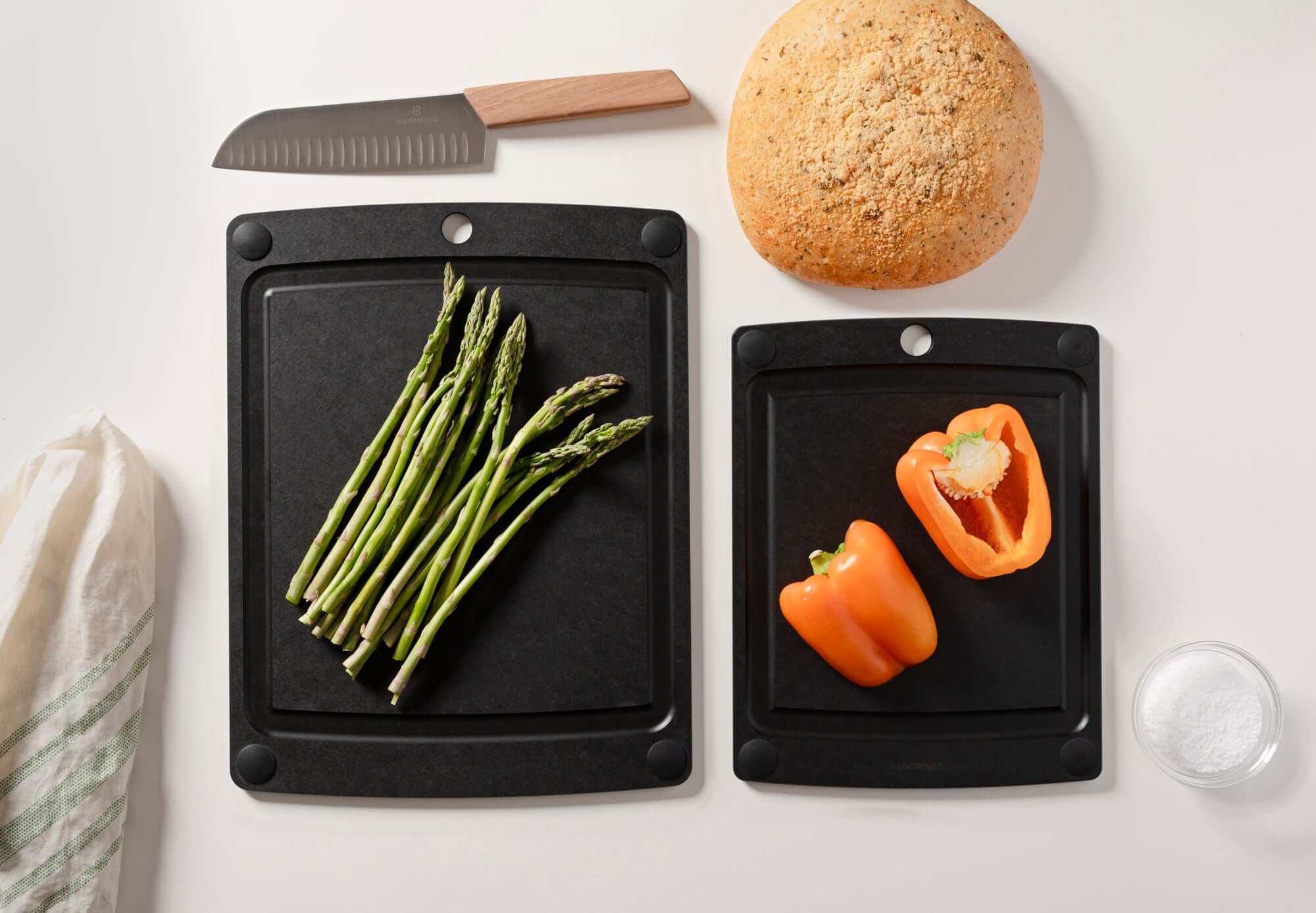 Up close detail of the All-in-One Cutting Board Set in Slate ready for meal prep with fresh asparagus and peppers ready to be expertly chopped with a Victorinox Swiss Modern Chef's knife with wood handle