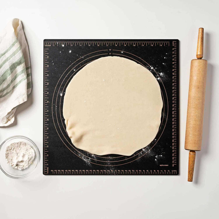 Epicurean Pastry Measuring Board in Slate precisely measuring a unbaked pie crust with a rolling pin, striped kitchen towel and flour