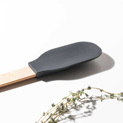 Close up of the Silicone Series Small Spoonula on a white background with herbs
