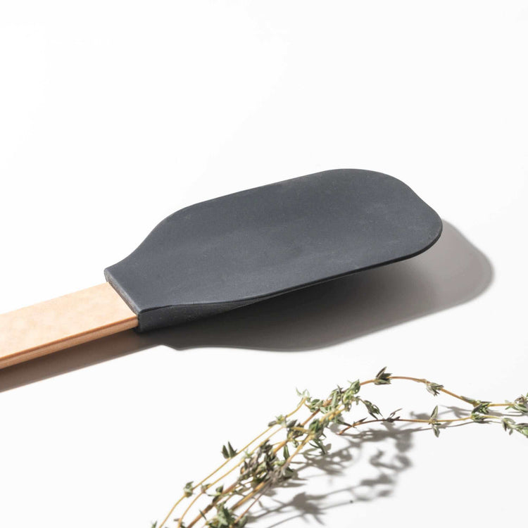  Close up of the Epicurean Silicone Series Large Spoonula Natural/Black on a white background with herbs