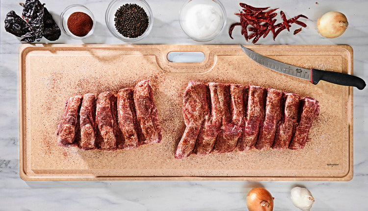 Big Game Cutting Board Natural With Rack of Ribs Being Prepped with a Onions, Pepper, Salt and a Victorinox Fillet Knife