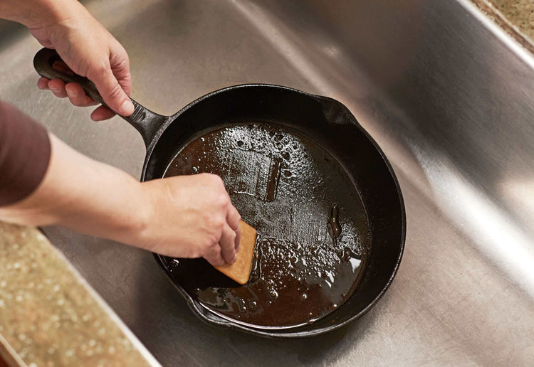 The Epicurean Pan Scraper in Natural being used to clean a cast iron pan. 